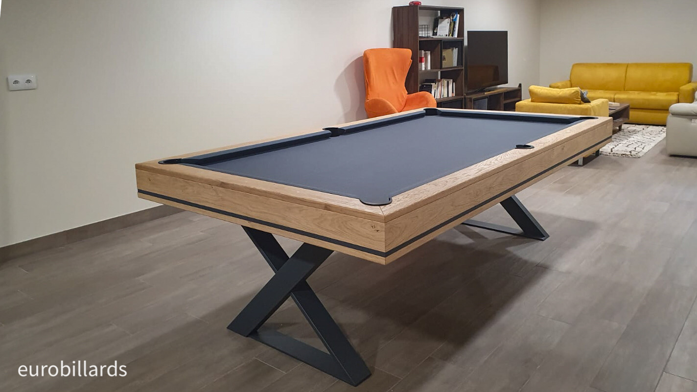 Le design contemporain du billard cross habillé de matériaux vénérables tels le chêne et le métal forgé rehaussé d'un liseré assorti, posent avec rafinement le côté design de cette salle de loisir où se cotoient parquet et canapé en cuir.